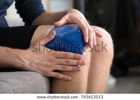 Close-up Of A Person Sitting And Applying Ice Gel Pack On An Injured Knee Royalty-Free Stock Photo #743652013