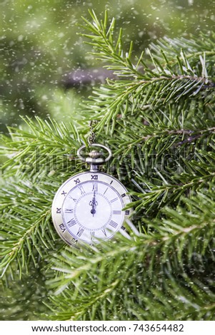 Christmas tree background and Christmas decorations with snow, blurred, sparking, glowing. Happy New Year Xmas theme. Vintage Clock and fir branches covered with snow. Time concept. Winter is coming.