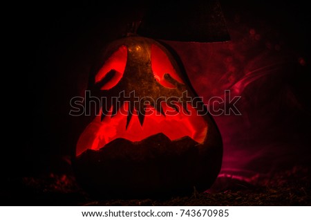 Halloween pumpkins smile and scrary eyes for party night. Close up view of scary Halloween pumpkin with eyes glowing inside at black background. Selective focus