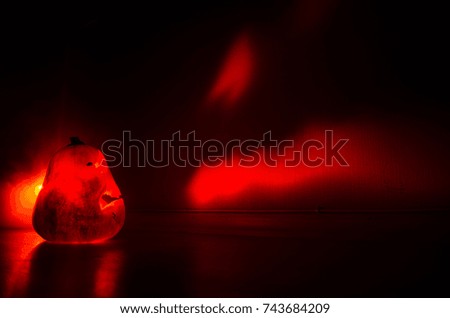 Halloween - terrible pumpkin on black background. Halloween glowing pumpkins border with leaves over warm wooden background, autumn holiday, traditional party decoration, horror concept
