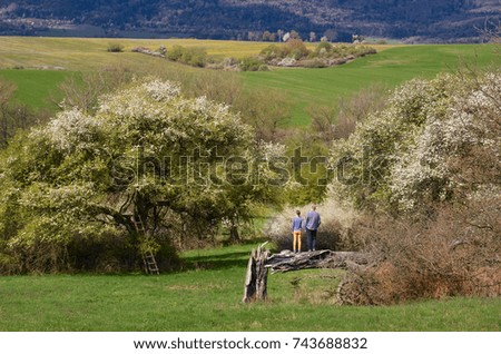 Man and woman on date in spring nature. Both sitting together on the tree and looking to somewhere. Photo full of love.