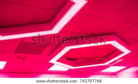 big bright red coral hexagon with light inside is on ceiling with classic office squares in Modern Design Studio, large hexagon chandelier against geometric ceiling as a decor modern element