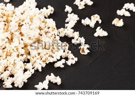 Popcorn banner with kernels lying on dark background with copy space for cinema card or flyer.