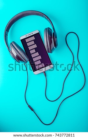 The equalizer on the screen of the phone with headphones playing music on a blue background
