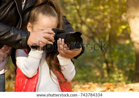 little girl is holding a camera and taking a photo. hobby. nature photography