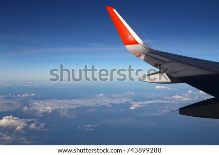 Beautiful  windows view when travel with  airplane, this picture see a wing of airplane, some clouds and blue sky.