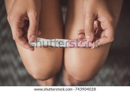 Cropped image of woman holding a pregnancy test on her knees Royalty-Free Stock Photo #743904028