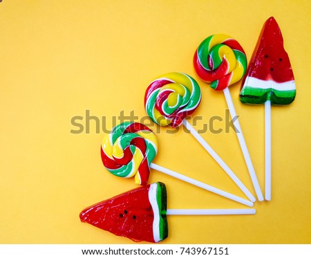 cute, bright, colorful round Lollipop and Lollipop in the shape of a watermelon, handmade on yellow background