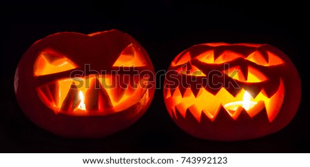 two spooky halloween jack-o-lanterns on black background. spooky pumpkins with candles inside