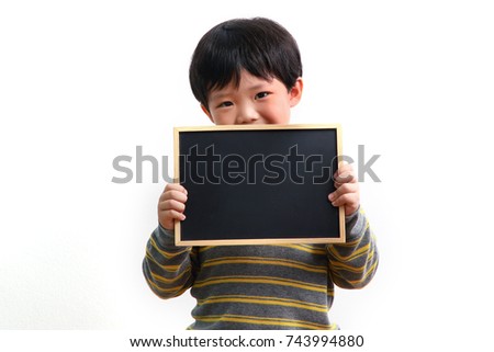 Cute little Asian boy holding a blank chalk board on white background.