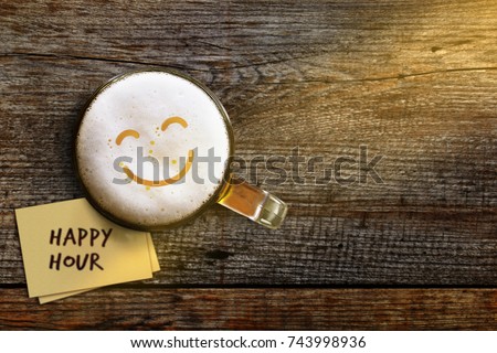 Happy Hour Concept for Bar, Cafe or Night club to Promote a Special Offer, Smiley Face on Foam in Glass of Beer over Wooden Table and Sticky Note, Top View