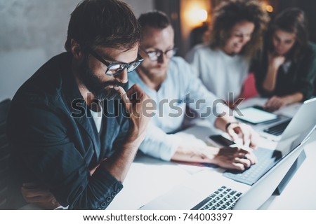 Teamwork concept.Project team making conversation at meeting room at night office.People using laptops and gadgets.Horizontal.Blurred background.Flares effect Royalty-Free Stock Photo #744003397