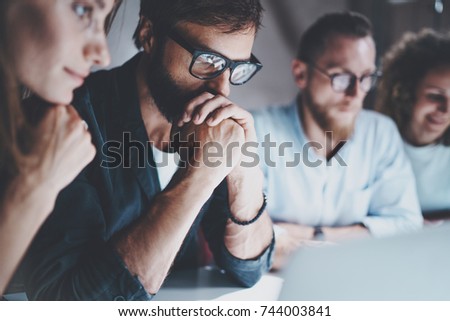 Group of young entrepreneurs are looking for a business solution during work process at night office.Business people meeting concept.Blurred background.Horizontal.Cropped