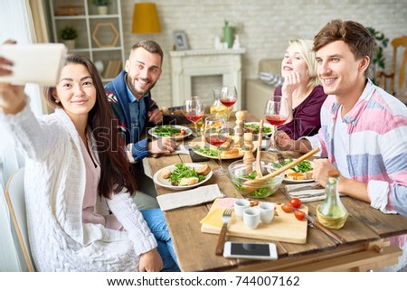Portrait of happy friends taking selfie sitting at dinner table while celebrating festive occasion