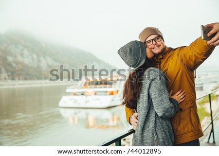 couple standing near river boat with mountain on bckground in fog