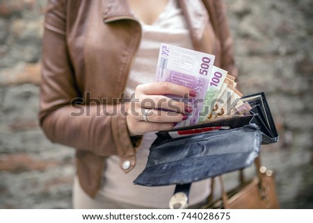 woman taking euro money from black wallet. City girl is taking out money from wallet. Woman hands holding European bank notes