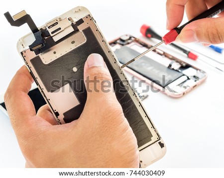Close-up of technician being unlock screw with screwdriver on blurred smartphone component background