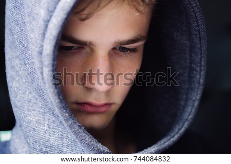 portrait of a serious teenage boy on a dark background, teenage  problem concept Royalty-Free Stock Photo #744084832