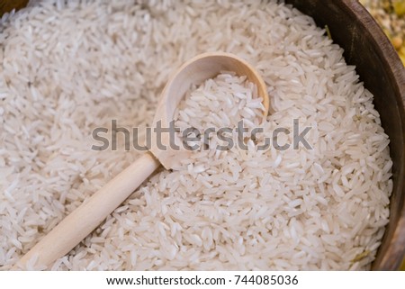 Raw white rice in wooden bowl and spoon on burlap, food ingredient photo