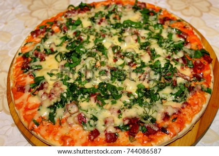 Pizza with sausage cheese and green onions lies on a round wooden cutting disc. freshly baked juicy pizza