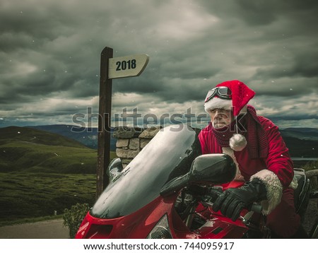 Santa Claus on a red heavy motorcycle at the top of the mountains with pointer with text 2018 Royalty-Free Stock Photo #744095917