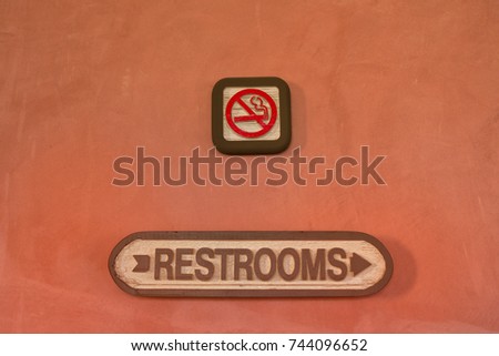 No smoking sign and restroom sign on the orange wall