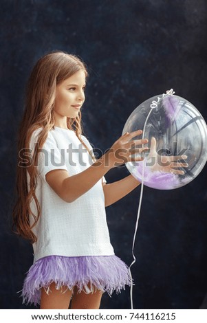 Beautiful little girl with wavy hair posing in a dress