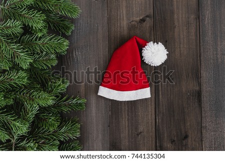 Christmas fir tree branches with santa claus hat on dark rustic wooden background with copy space for text