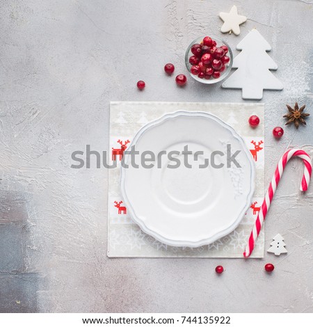 Christmas decor of the table. White blank plate for your text. Funny napkins with reindeers Santa Claus. 
Flat lay, top view