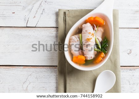 Squid stuffed with minced pork and soup in white bowl on table