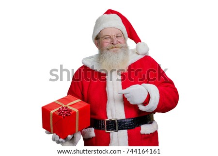 Portrait of Santa Claus with present. Man in costume of Santa Claus standing on white background and holding Christmas present. Santa pointig on red gift box with bow.