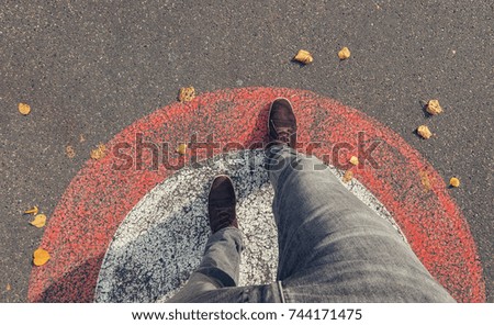 Young man in sneakers steps outside a circle at the streets, personal pespective  Royalty-Free Stock Photo #744171475