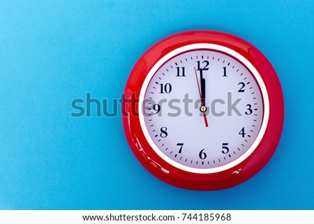 New year concept - Red wall clock pointing at 12 o'clock on blue background   Royalty-Free Stock Photo #744185968