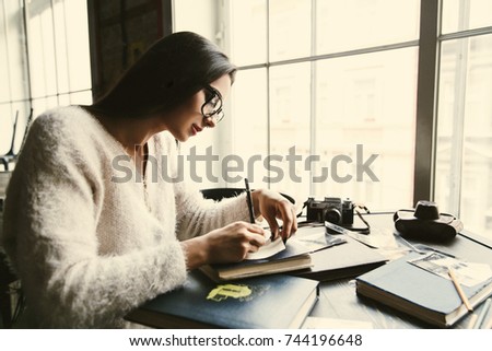 Thoughtful beautiful woman makes some notes sitting in the cafe