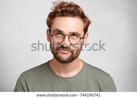 Portrait of stylish bearded man with bored fed up expression, looks displeased up, being tired to explain new material to his friend who can`t understand it. Puzzled male doesn`t know what to do Royalty-Free Stock Photo #744196741