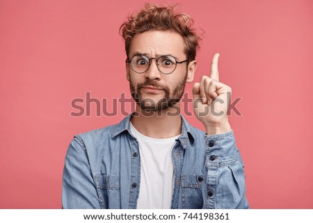 That is! Handsome clever student wonk or geek wears round glasses, raises finger as understands new theory, going to prove it, looks confidently, isolated over pink background. Confidence concept Royalty-Free Stock Photo #744198361