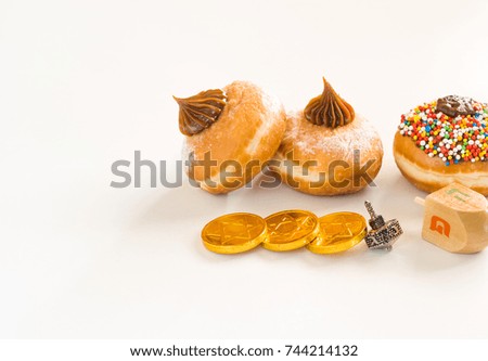 Fresh donuts with chocolate, wood and silver dreidels  and chocolate coins for Hanukkah celebration.