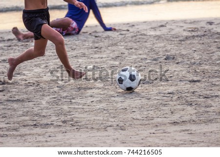 Boy group playing football on the beach in the evening.
