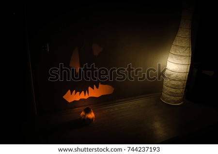 Halloween - terrible pumpkin on black background. Halloween glowing pumpkins border with leaves over warm wooden background, autumn holiday, traditional party decoration, horror concept
