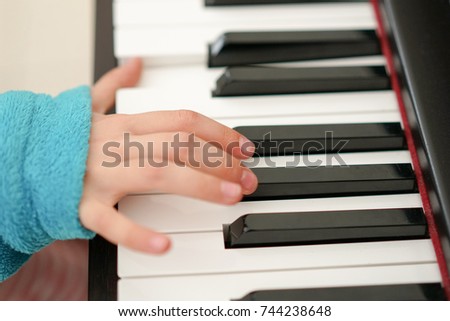Children's fingers on the keys of a piano playing