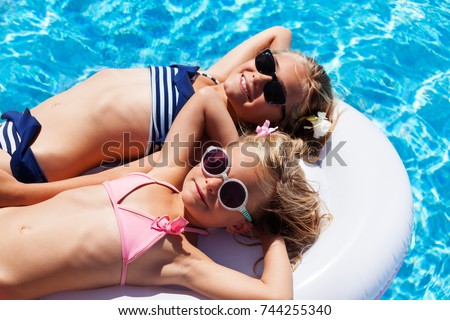 Happy girls relaxing on mattress in swimming pool