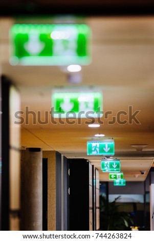 Row of green exit signs pointing to escape door in a modern office office