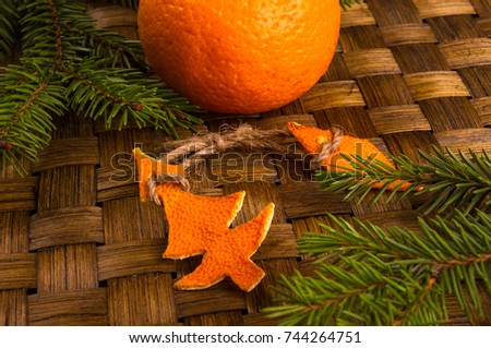 New Year Concept. Christmas decorations from tangerine peel, fir-tree branches and the fruits of mandarin orange on woven mat background