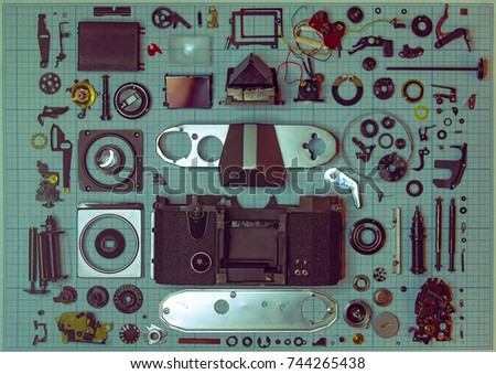parts are completely disassembled old retro film SLR camera on graph paper, close-up, toned