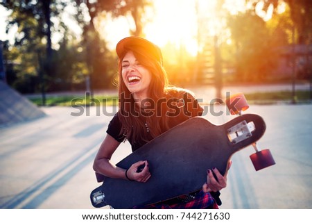 Teenager girl dancing with skateboard in hands warm color toned image