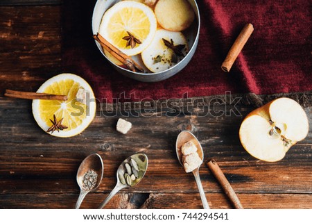 hot drink, mulled wine red, ingredients for mulled wine: orange, Apple, cinnamon, cloves, ginger in a bowl on wooden background Retro toned photo. Copy space for your text.