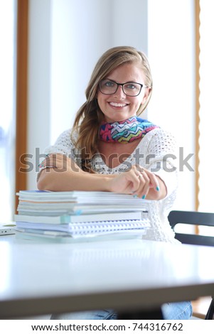 Young woman sitting at a desk among books. Student