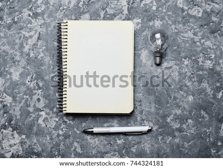 Hipster notepad, pen and incandescent bulb on a concrete table. I have an idea! Inspiration for the writer. Top view. Loft style.