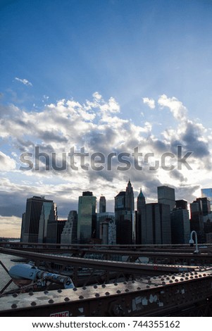 Financial district with Brooklyn Bridge’s structure under the shade and cloudy blue sky