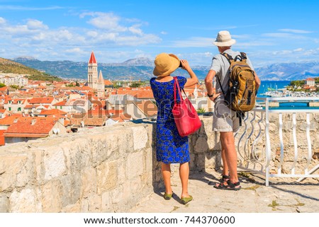 Couple of unidentified elderly tourists taking picture of Trogir town from castle walls, Dalmatia, Croatia